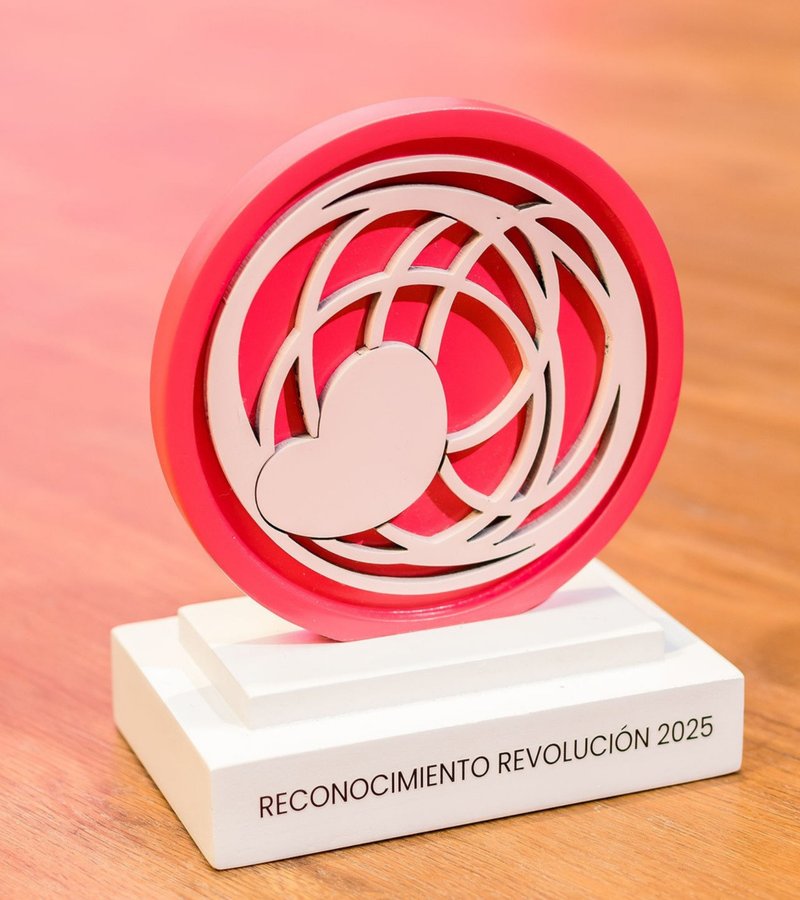 Trofeo Reconocimiento R-evolución 2025: círculo rosa con corazón sobre base blanca