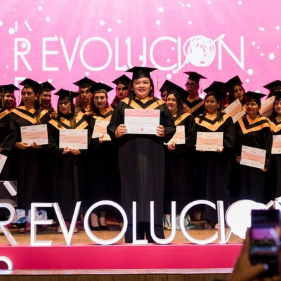 Graduadas de R-evolución con sus diplomas frente al letrero de R-evolución